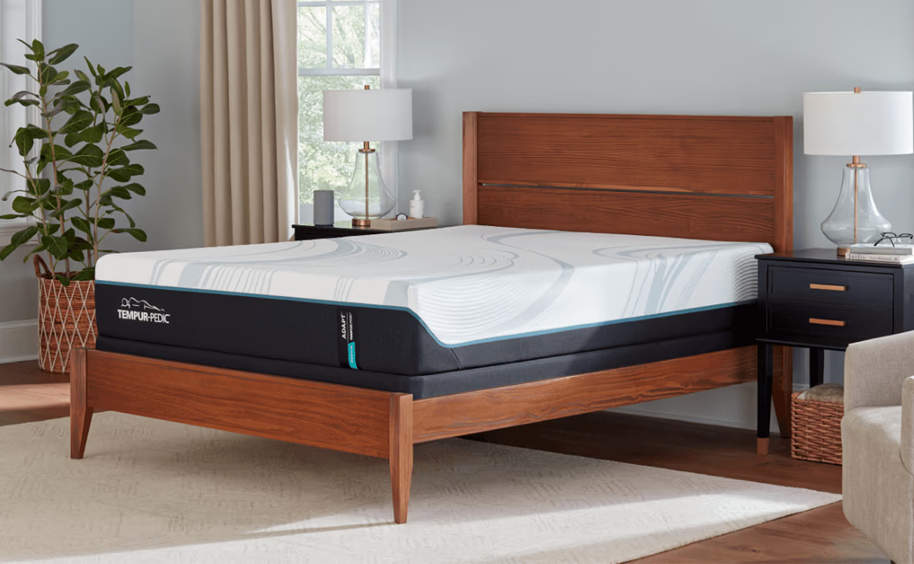 A Tempur-Pedic mattress on a mid-century modern wooden bed frame in a contemporary bedroom.